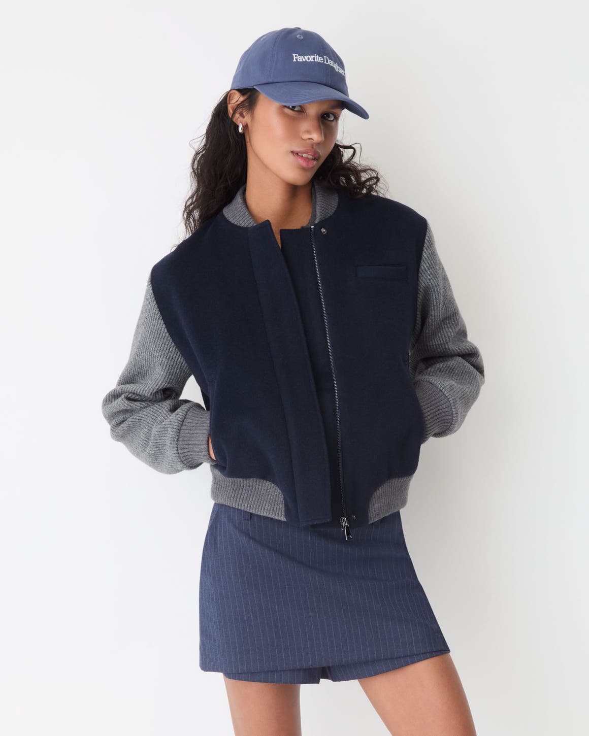 A girl wearing a letterman jacket and skirt.