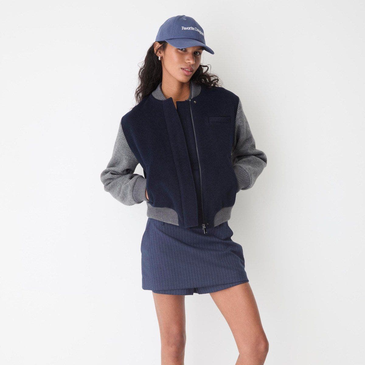 A woman wearing a baseball cap and a wool bomber jacket.