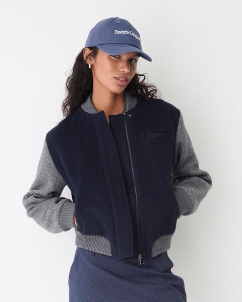 A woman wearing a baseball cap and a wool bomber jacket.