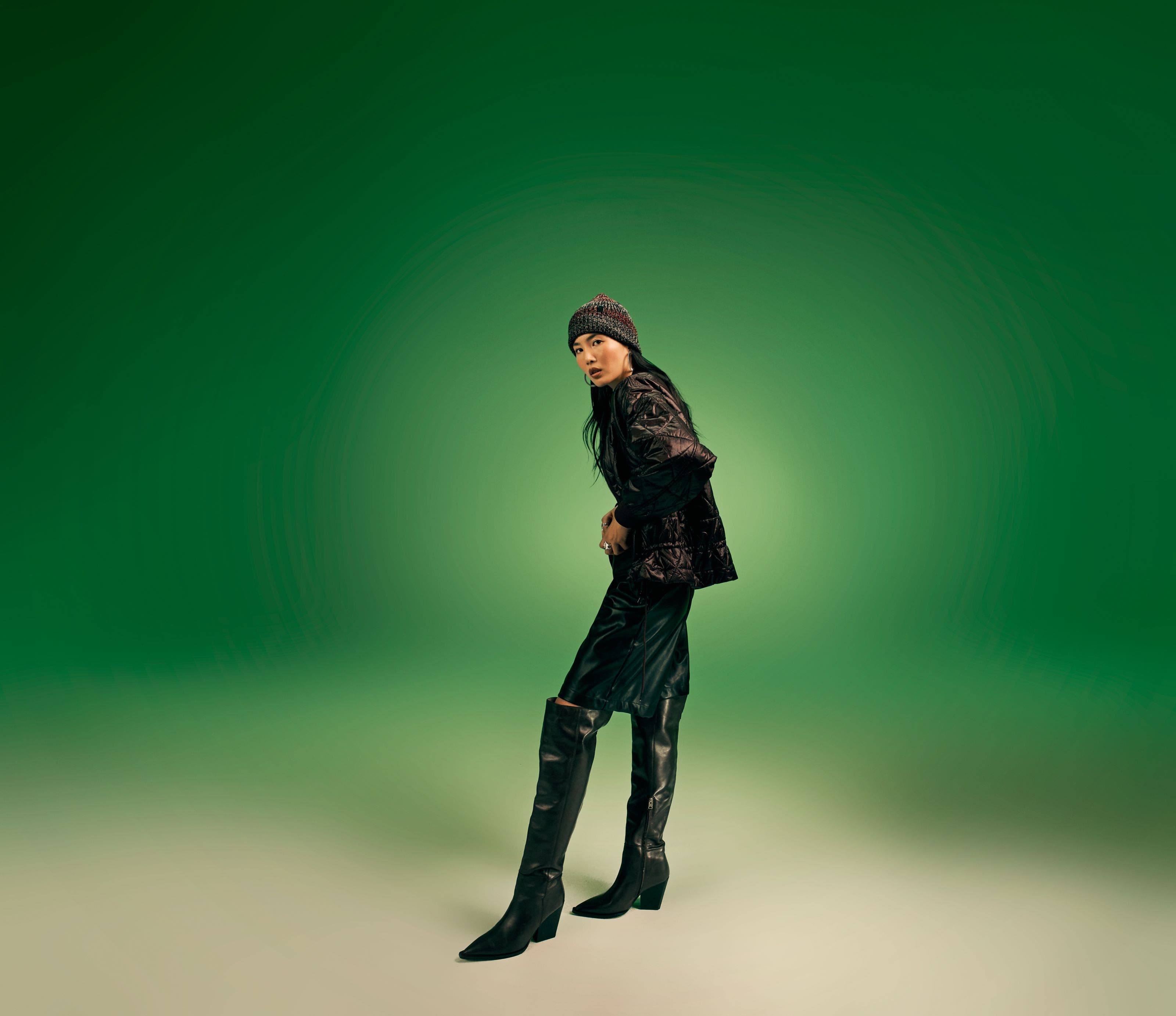 A woman wearing a black jacket, black shorts and black boots. 