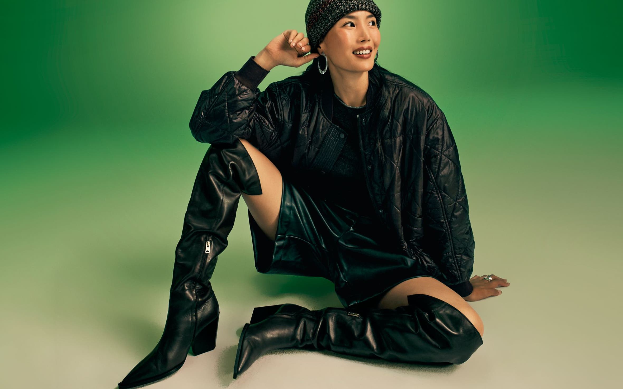A woman wearing thigh-high boots with black shorts and a black jacket.