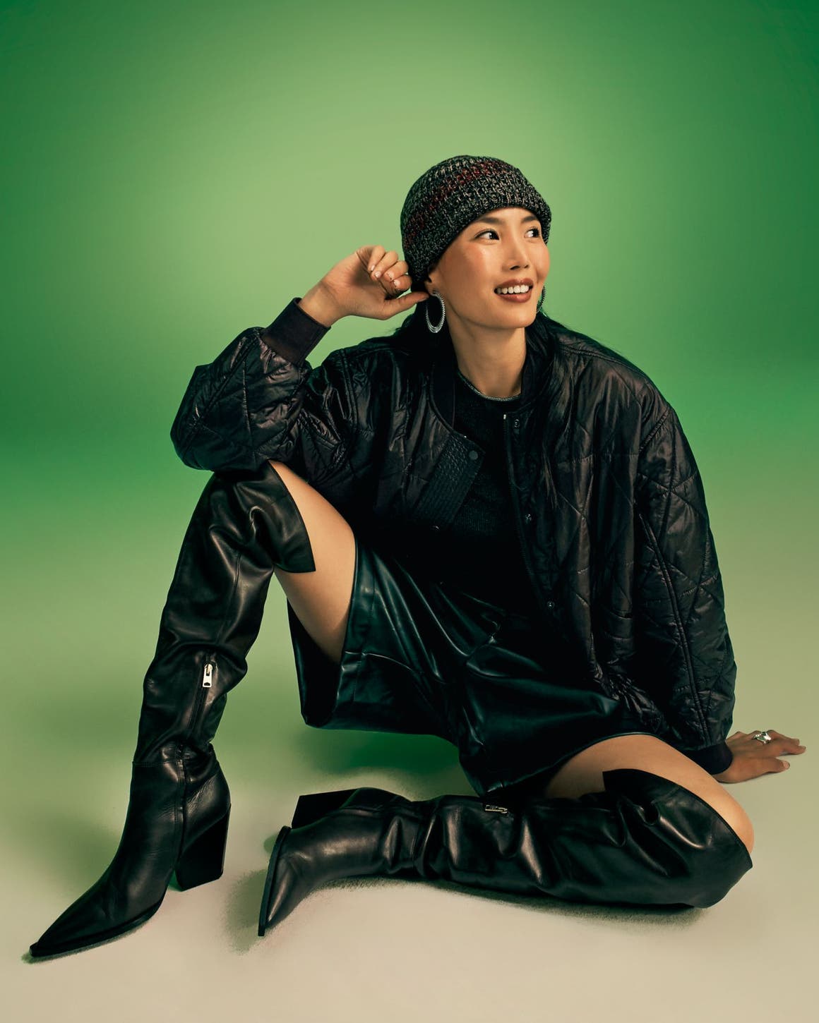 A woman wearing thigh-high boots with black shorts and a black jacket.