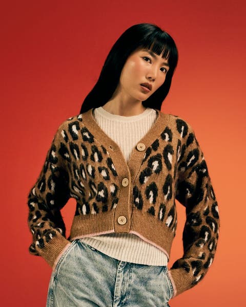 Woman in a leopard-print cropped cardigan and light-wash jeans.
