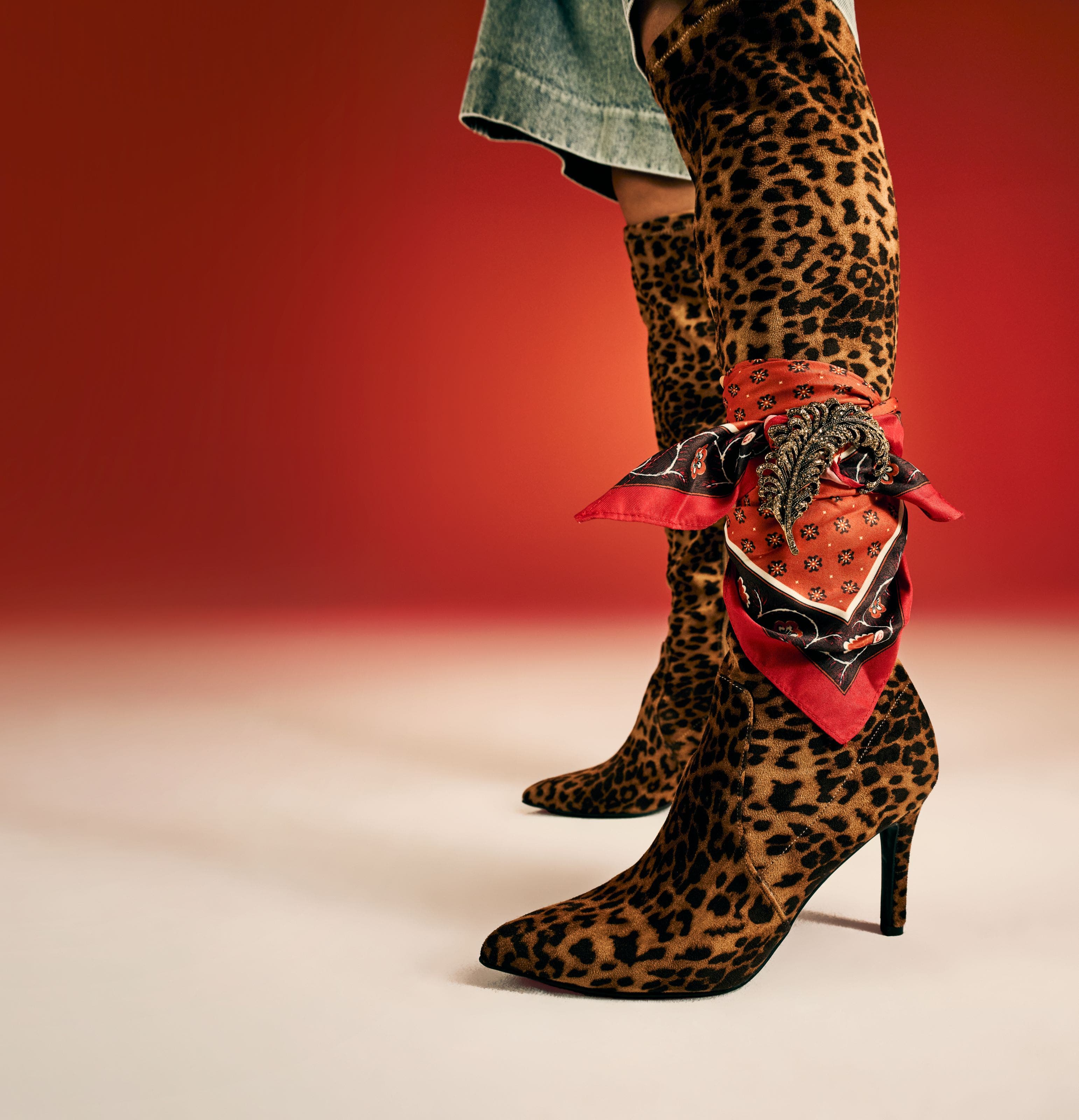 Leopard-print over-the-knee stiletto boots styled with a red silk scarf.