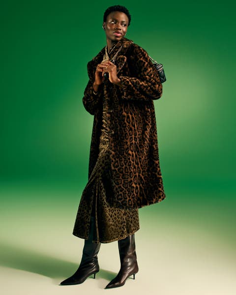 Woman in a long leopard-print coat and black boots on green.