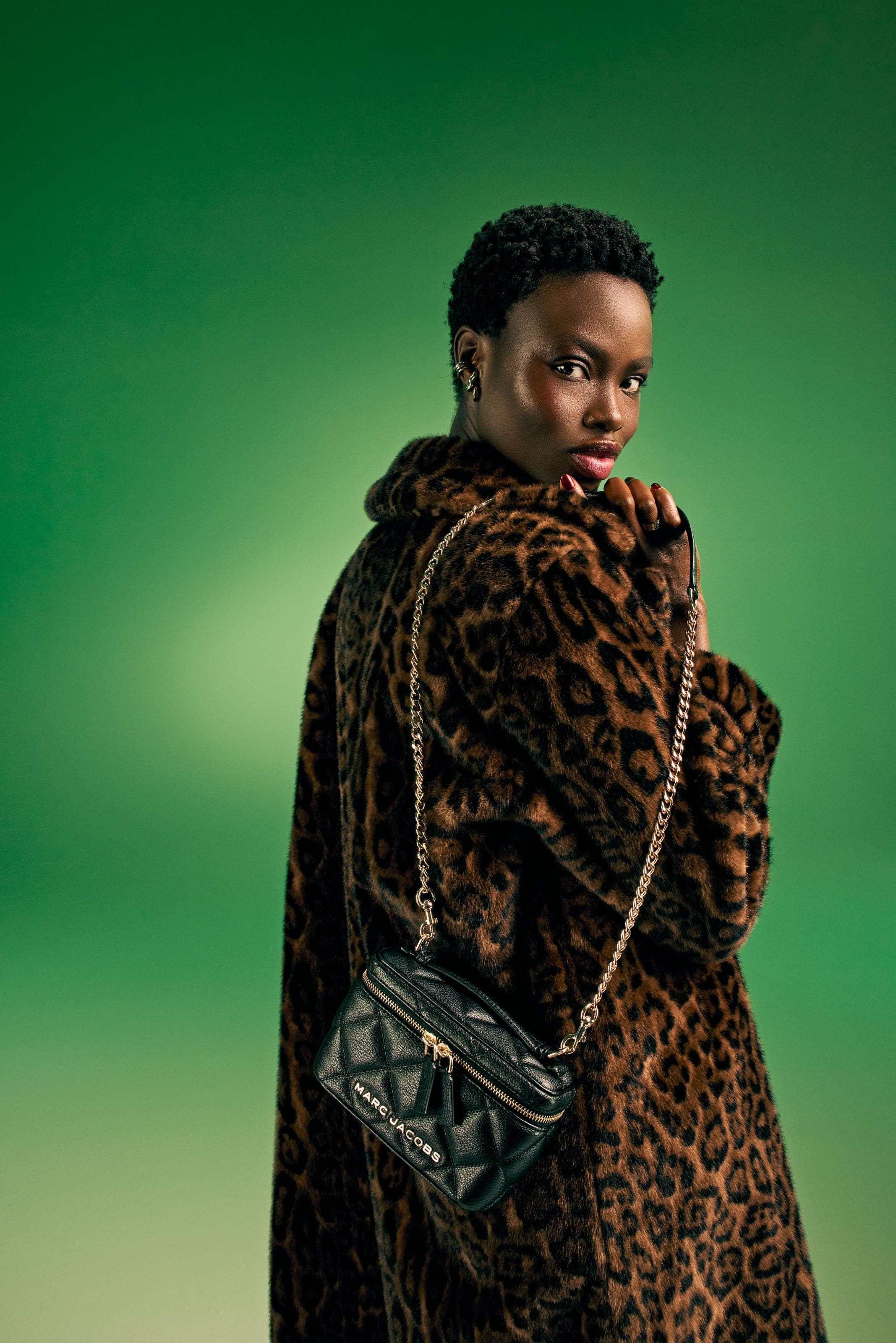 Woman in a leopard-print coat with a black chain-strap bag.