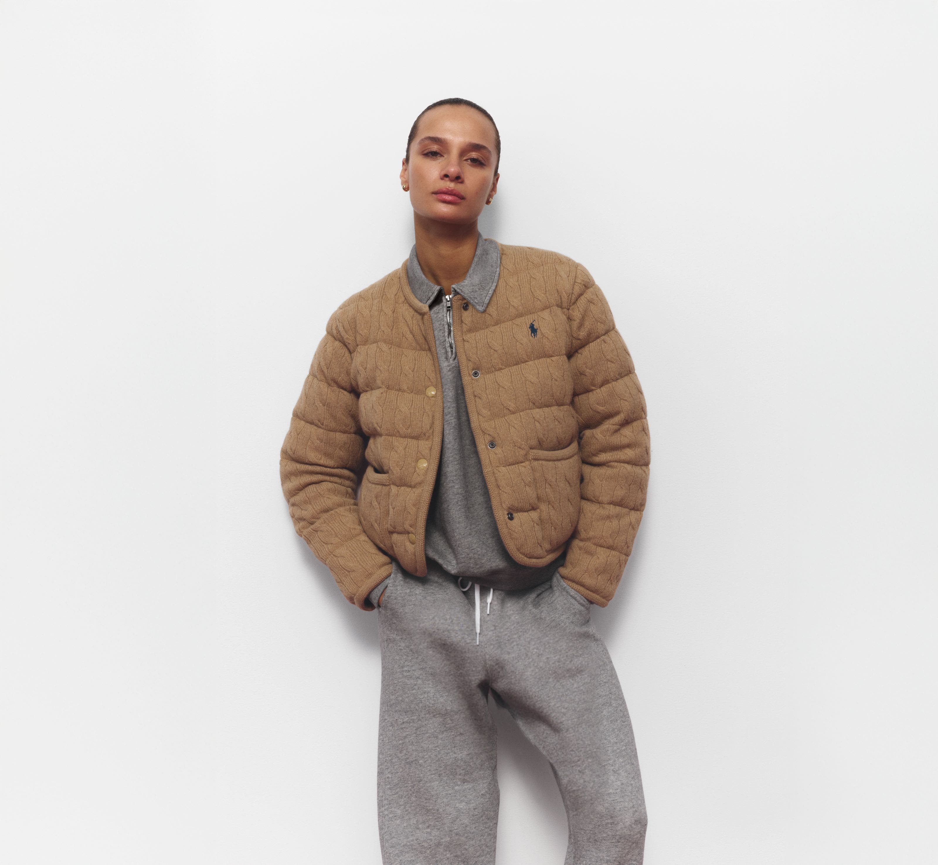 A woman wearing a sweatshirt and matching joggers with a quilted jacket.