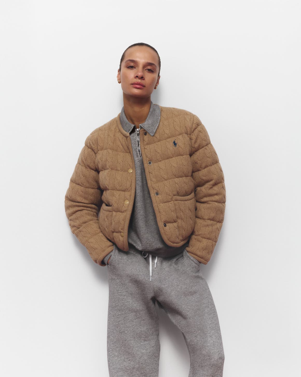 A woman wearing a sweatshirt and matching joggers with a quilted jacket.