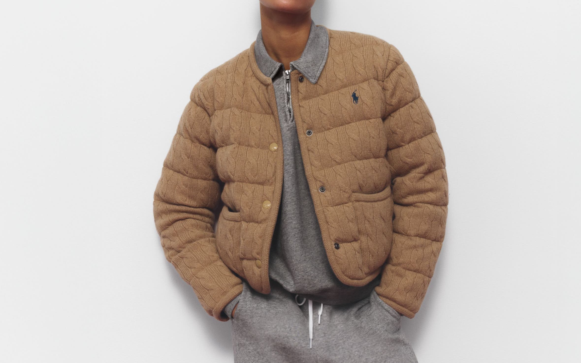 A woman wearing a sweatshirt and matching joggers with a quilted jacket.