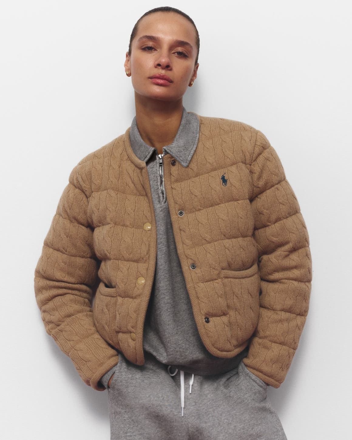 A woman wearing a sweatshirt and matching joggers with a quilted jacket.