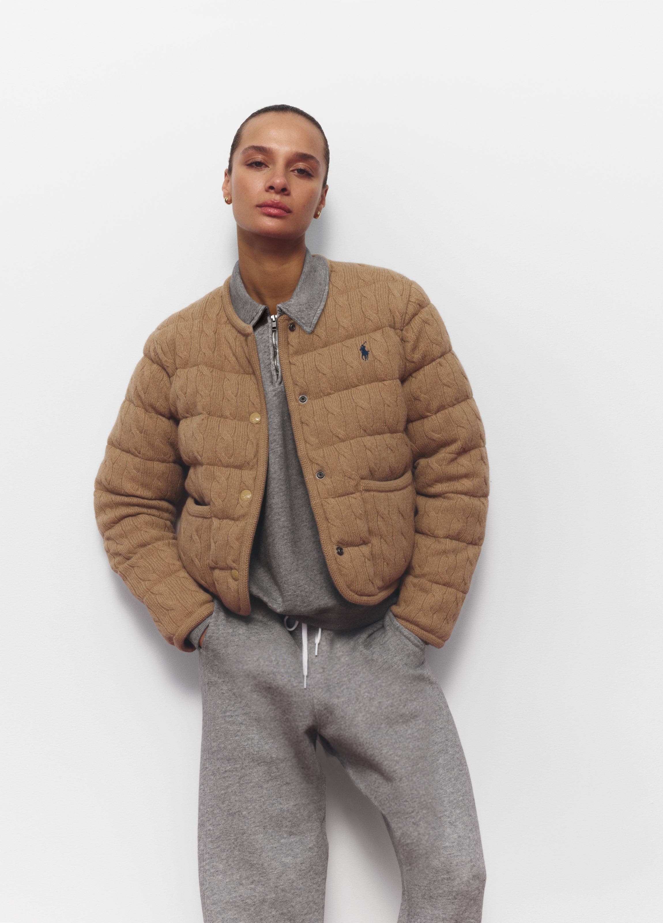A woman wearing a grey sweatsuit and lightweight puffer jacket.
