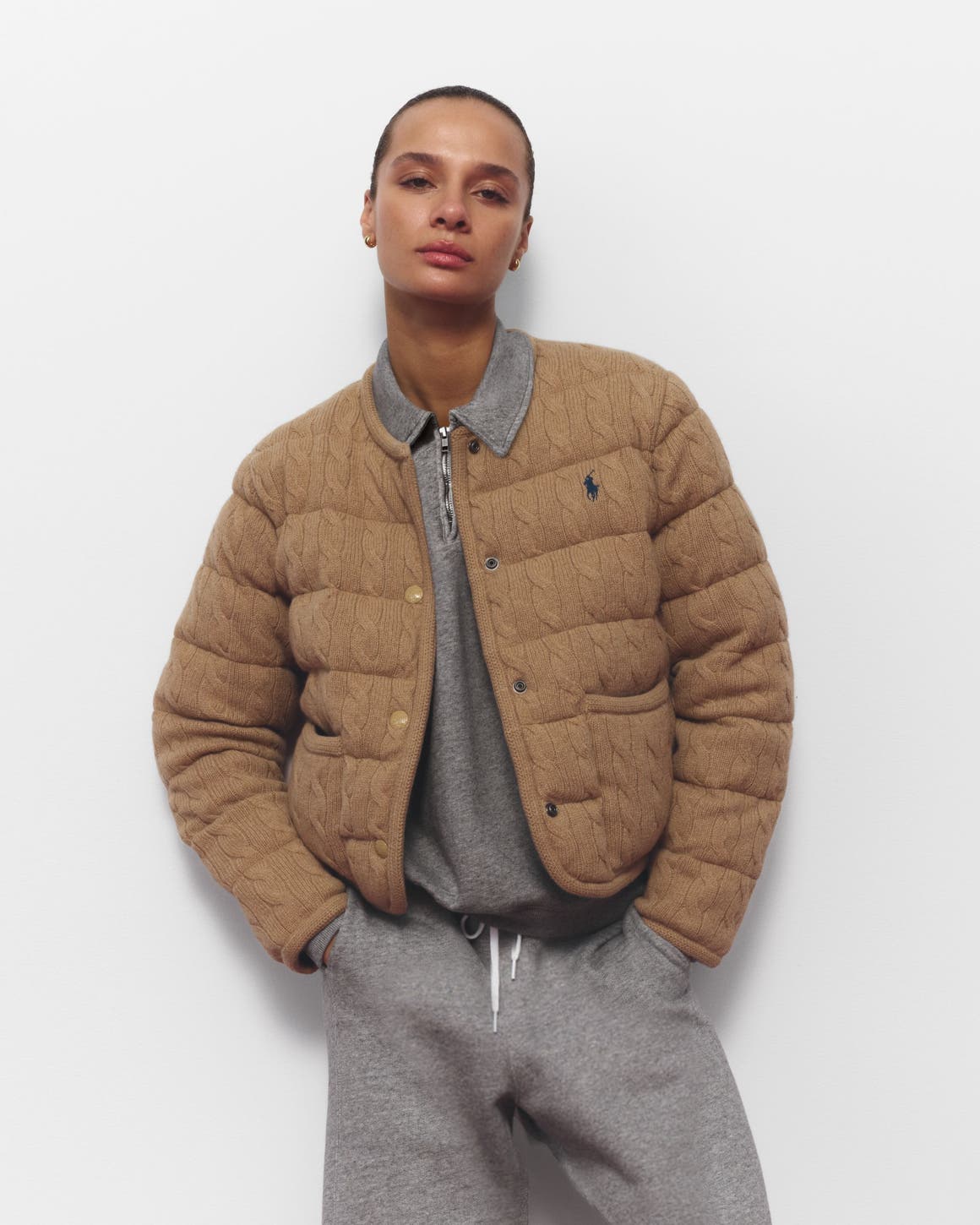 A woman wearing a grey sweatsuit and lightweight puffer jacket.