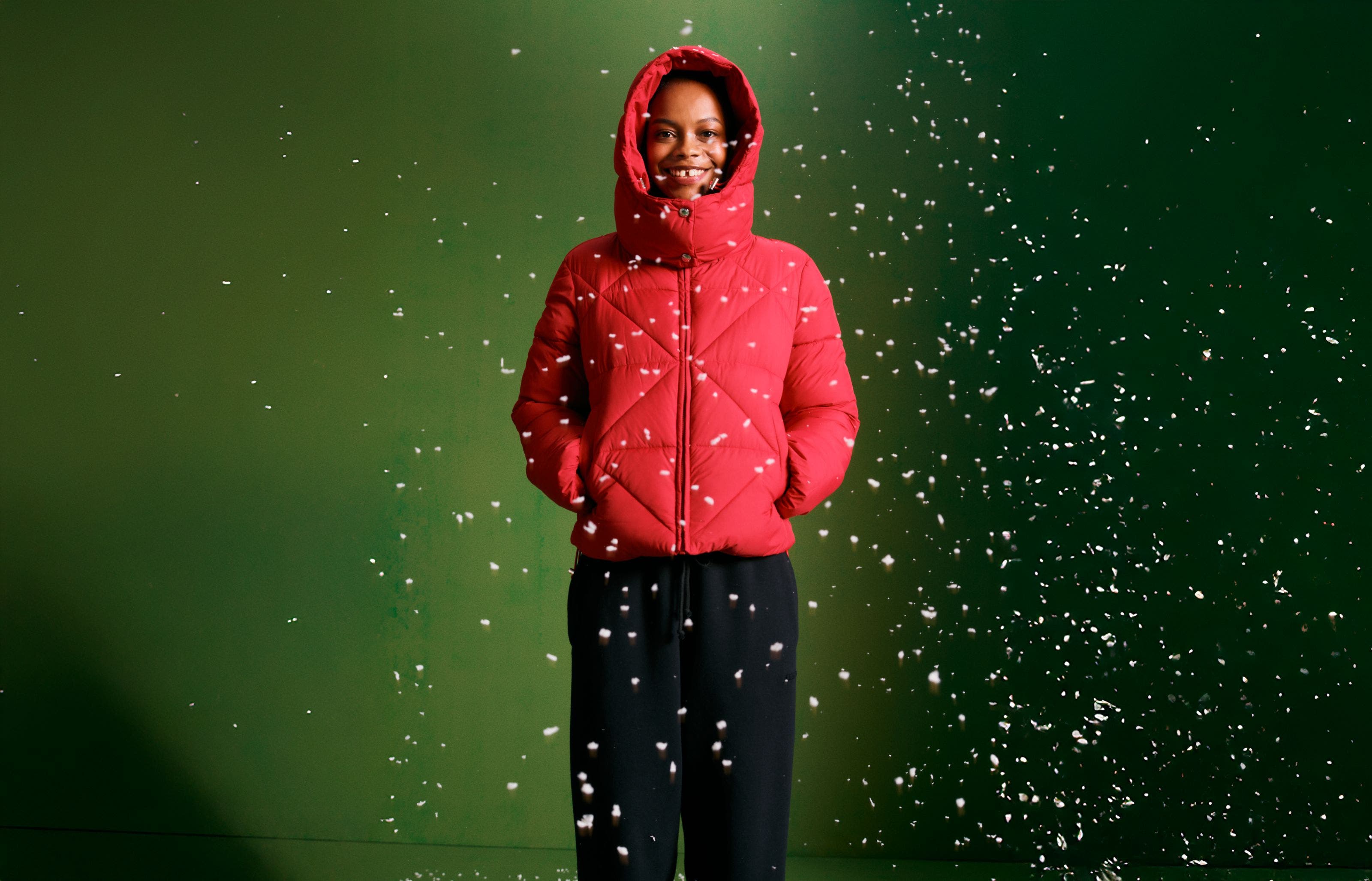 A woman wearing a red puffer jacket and sweatpants.