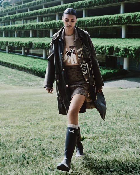 Woman wearing a bomber jacket, tiered skirt, bucket bag and boots.