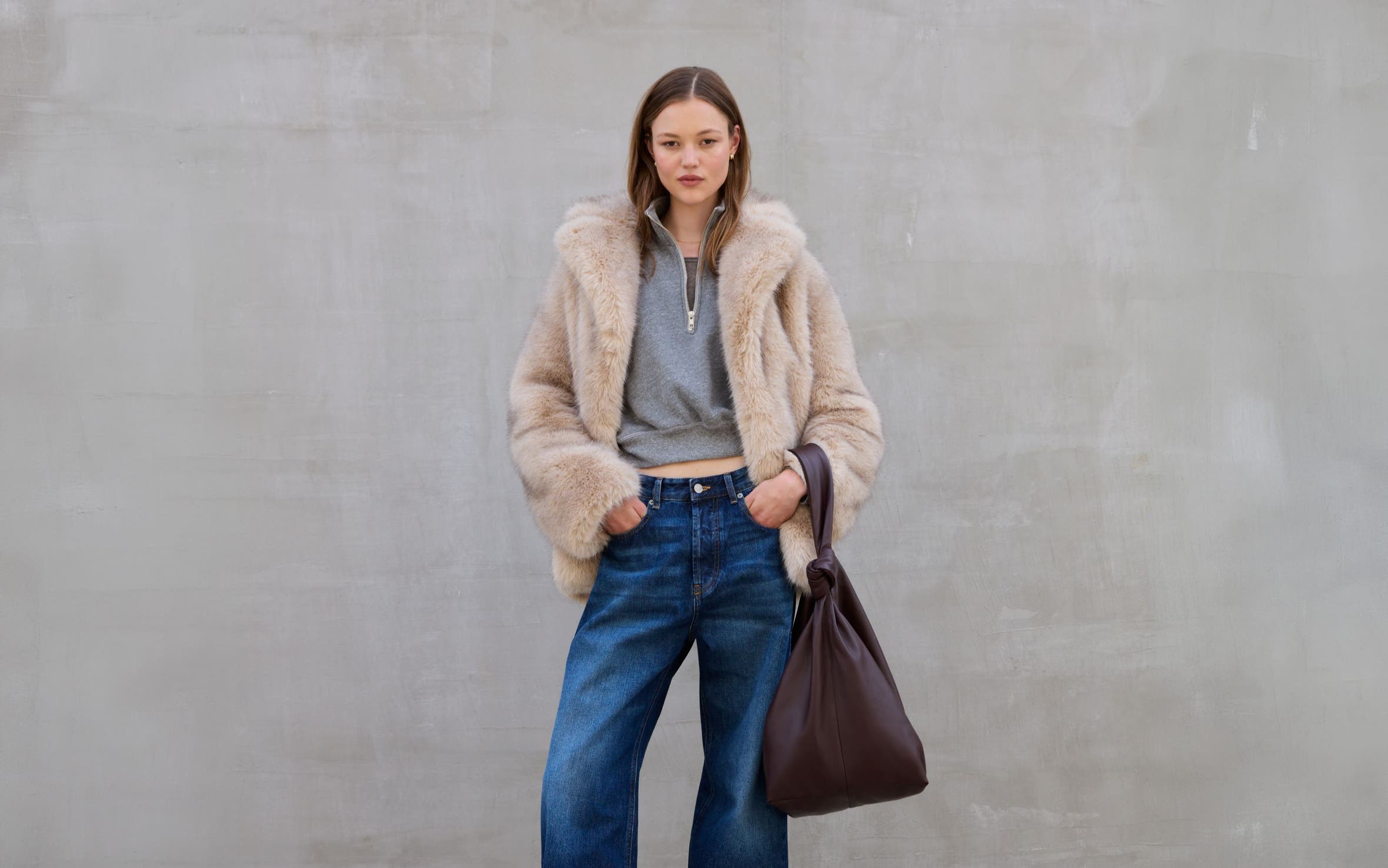 A woman wearing a fuzzy jacket and jeans.