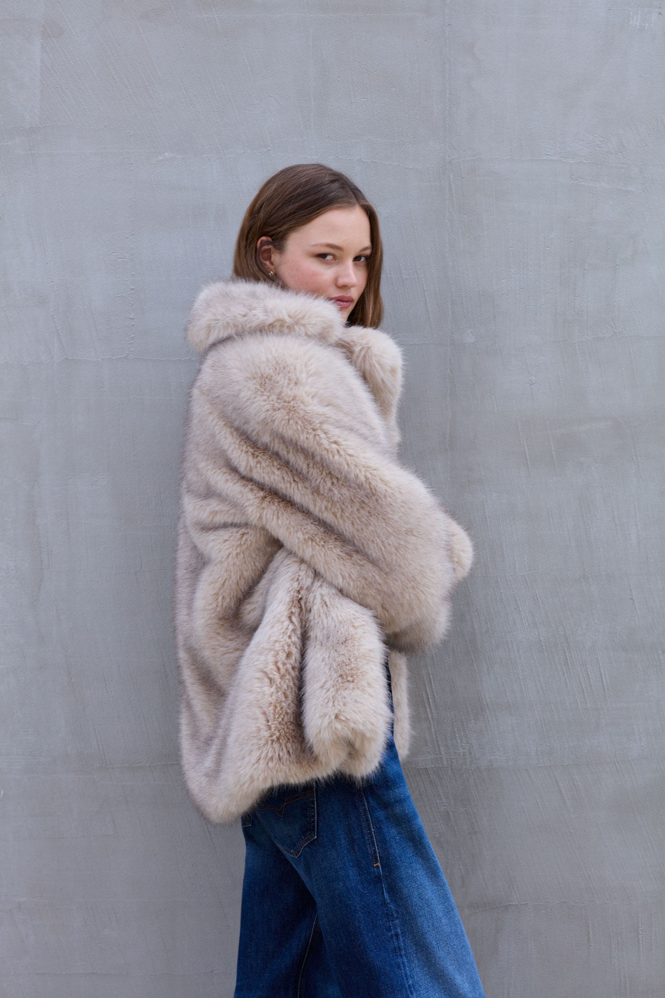 A woman wearing a tan faux fur jacket.