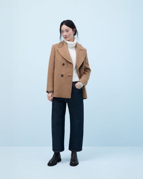 Woman wearing a peacoat, turtleneck sweater, jeans and boots.