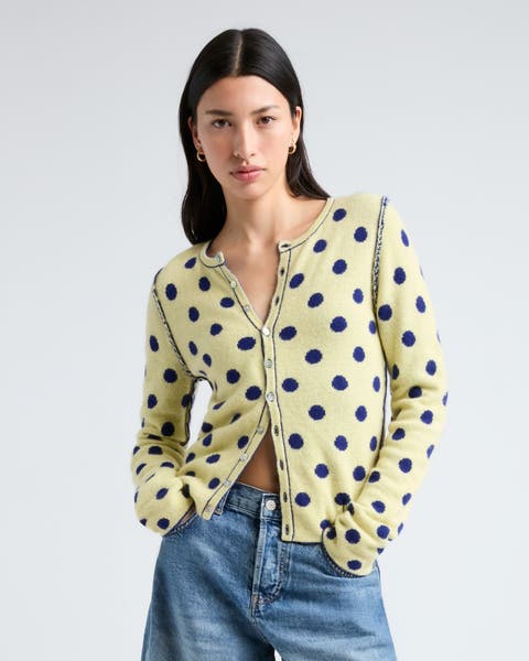 woman in denim shorts wearing a polka dot cardigan.