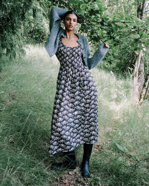 Woman wearing a cardigan, plaid dress and suede boots.