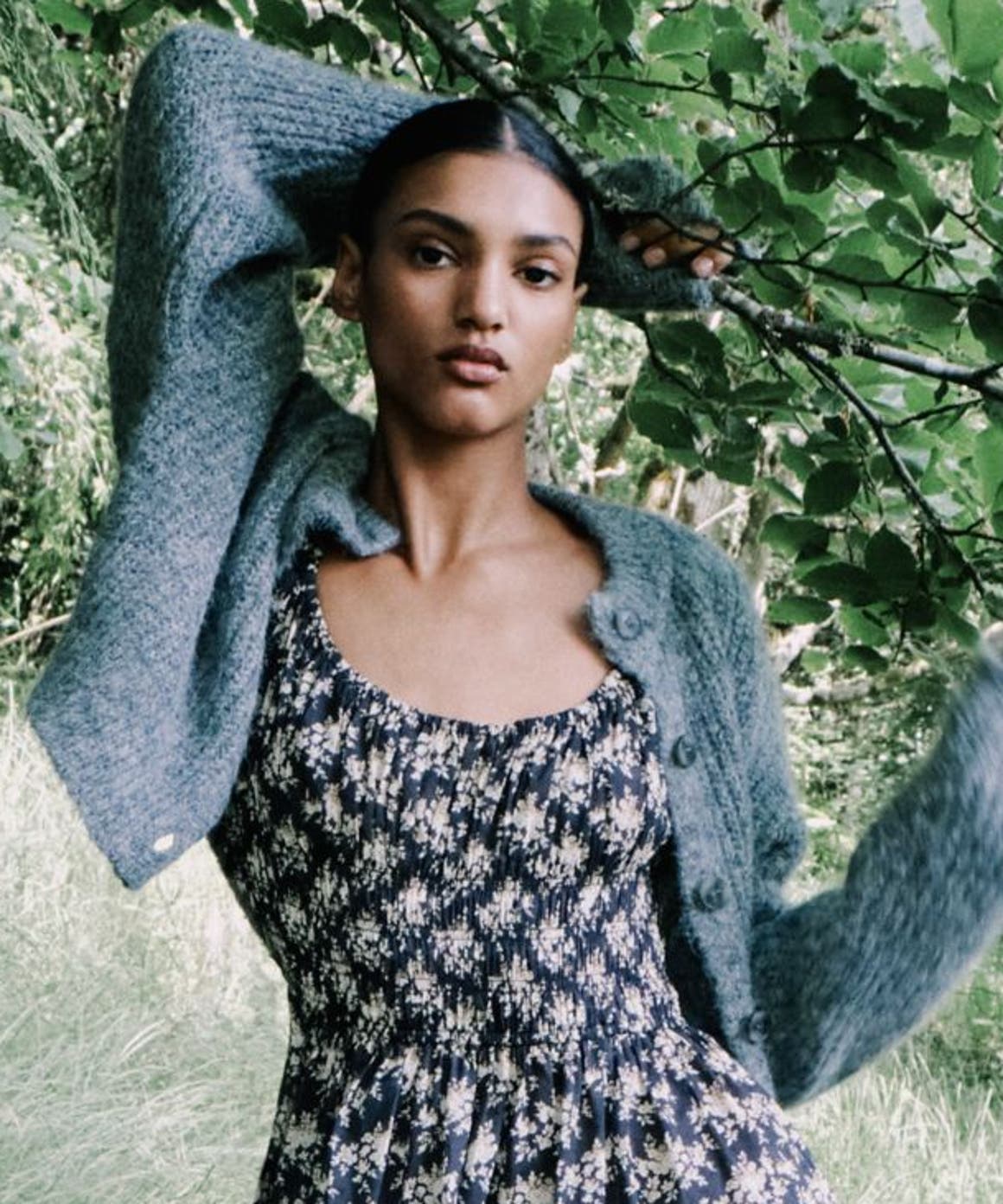 A woman holding onto a tree branch.