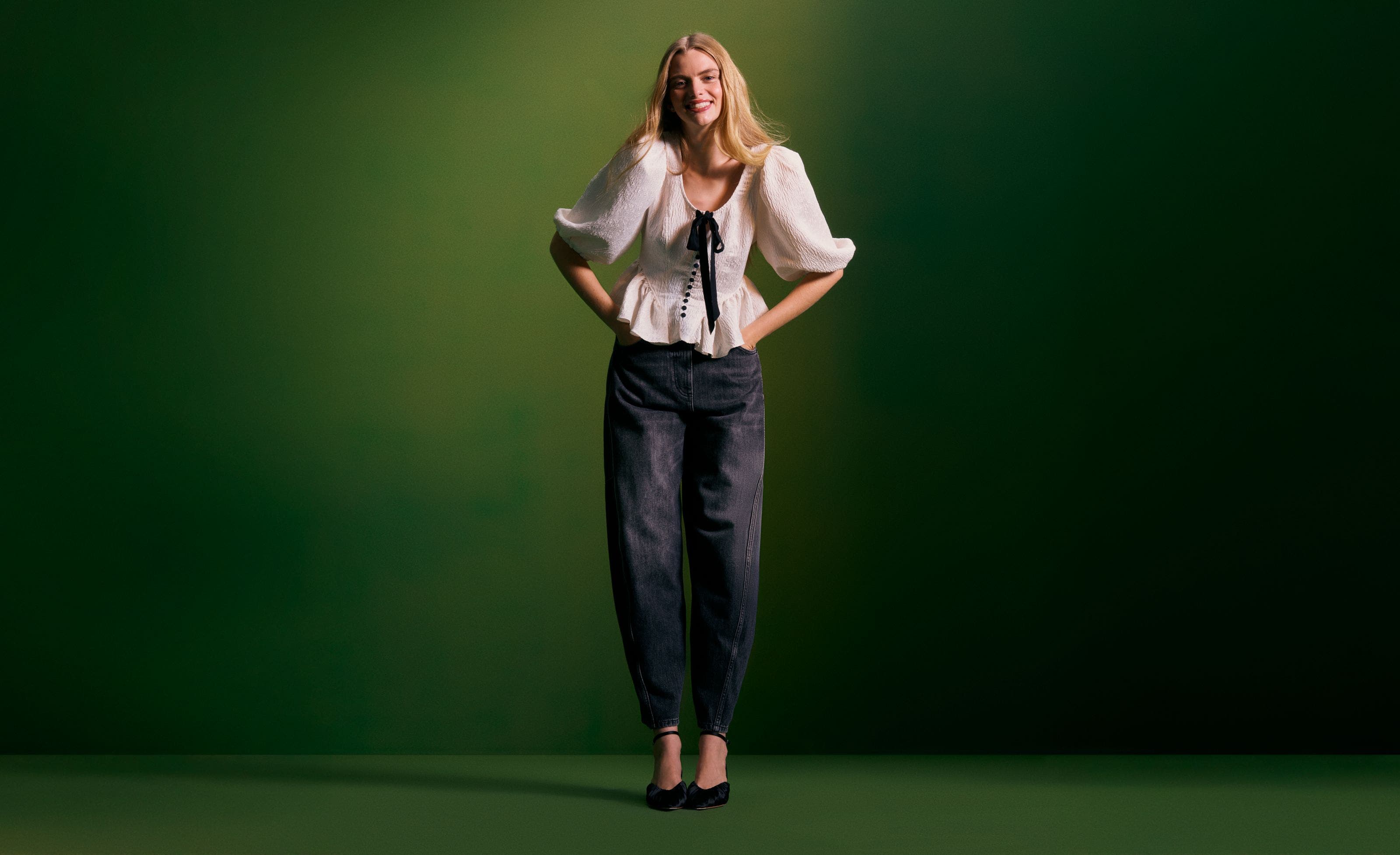 A woman wearing a white top with a bow detail and ruffled hem.