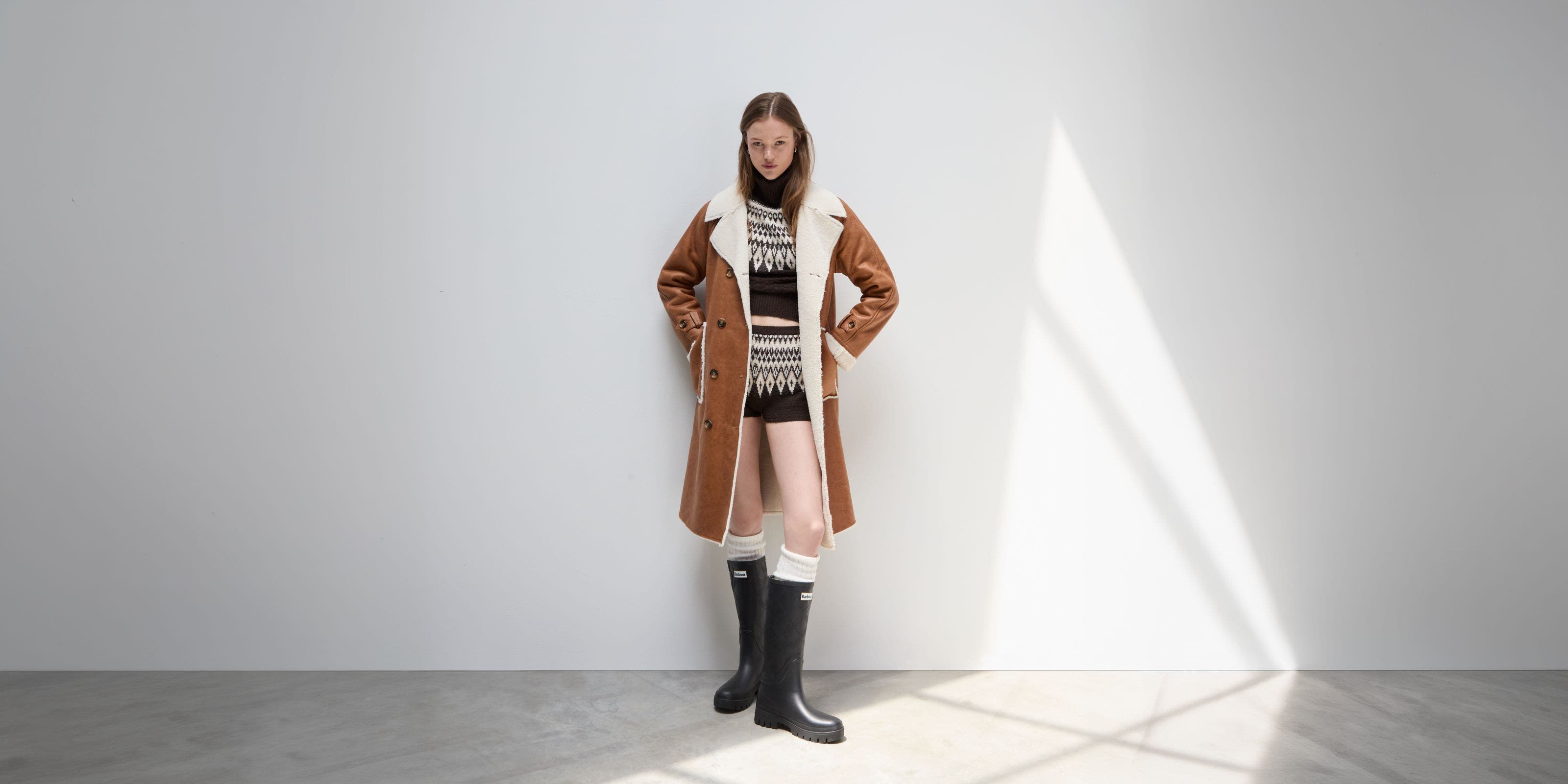 A woman wearing a coat, knit set, and boots.