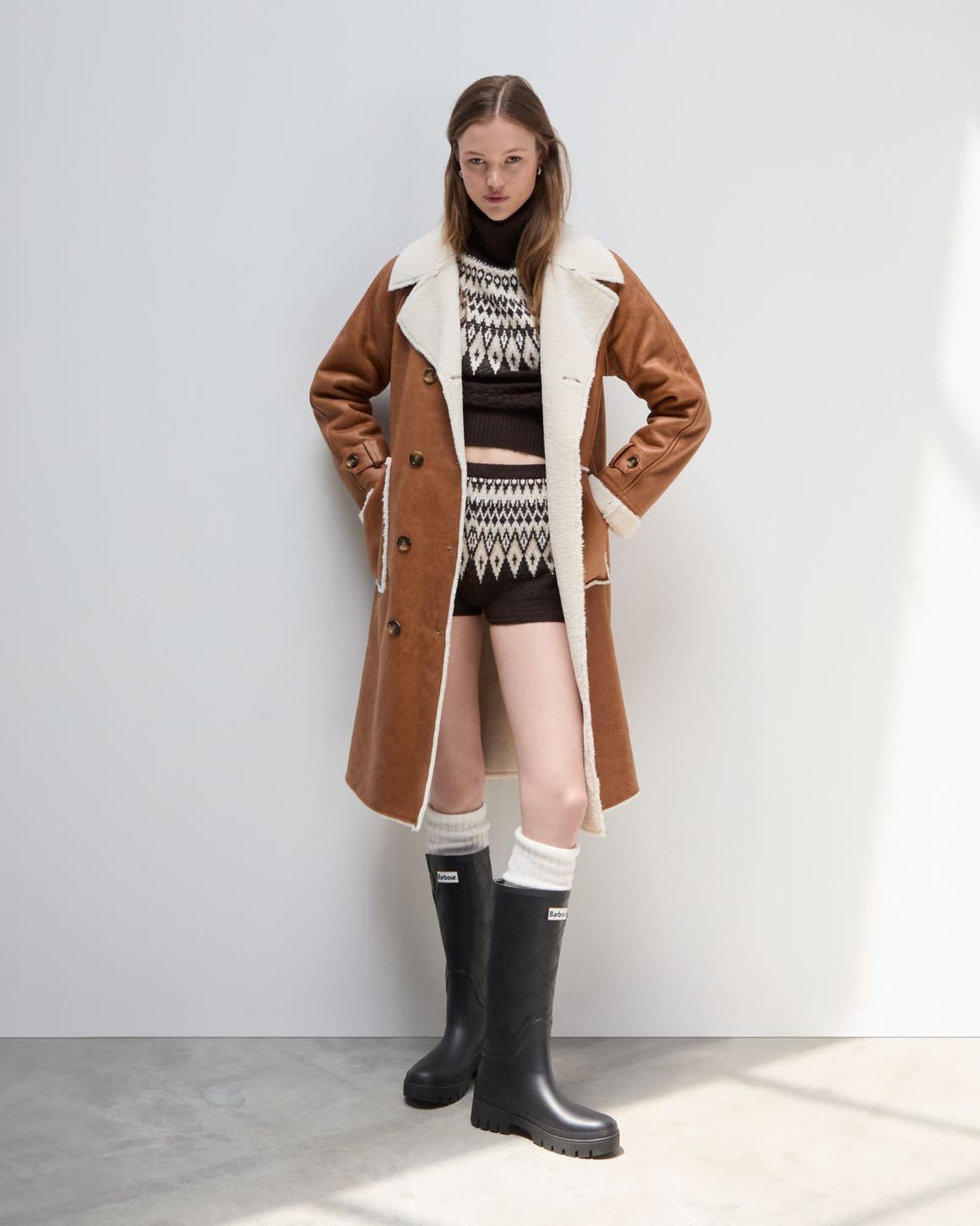A woman wearing a coat, knit set, and boots.