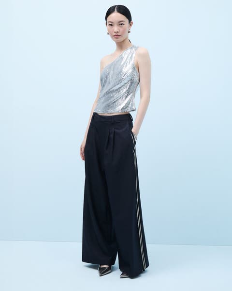 A woman wearing a sparkly silver one-shoulder top and trousers.