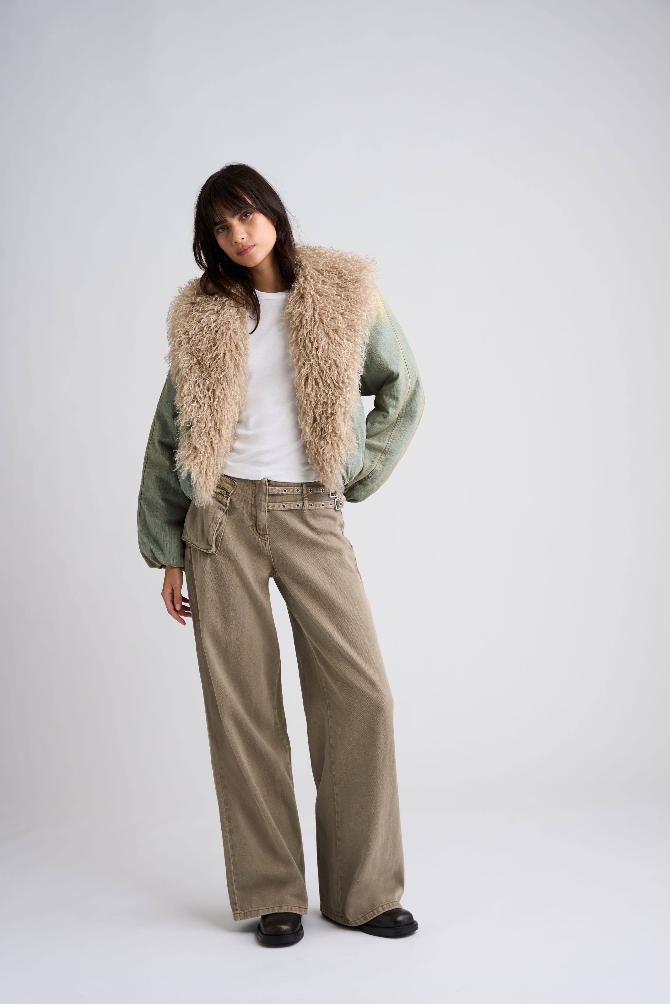 A woman in a shearling-trim jacket and white tee.
