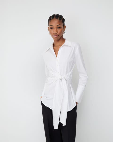 Woman wearing a white shirt with a sash and black pants.