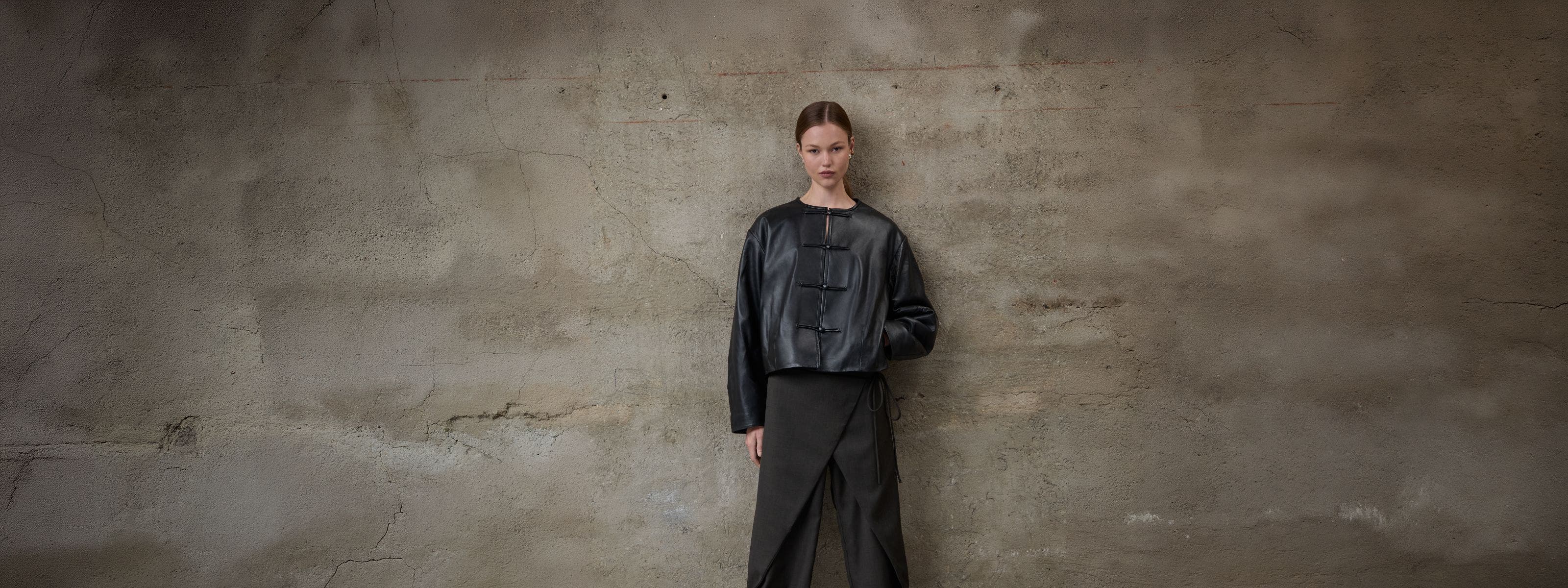 A woman wearing a leather jacket and trousers.