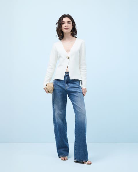 Woman wearing a top, jeans, heels and evening clutch.