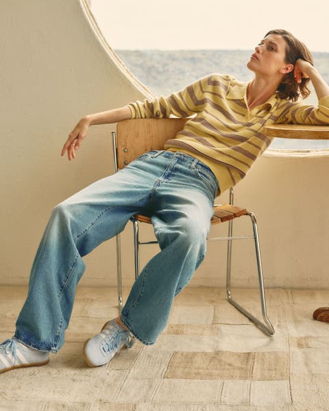 Woman wearing a striped polo top, wide-leg jeans and sneakers.