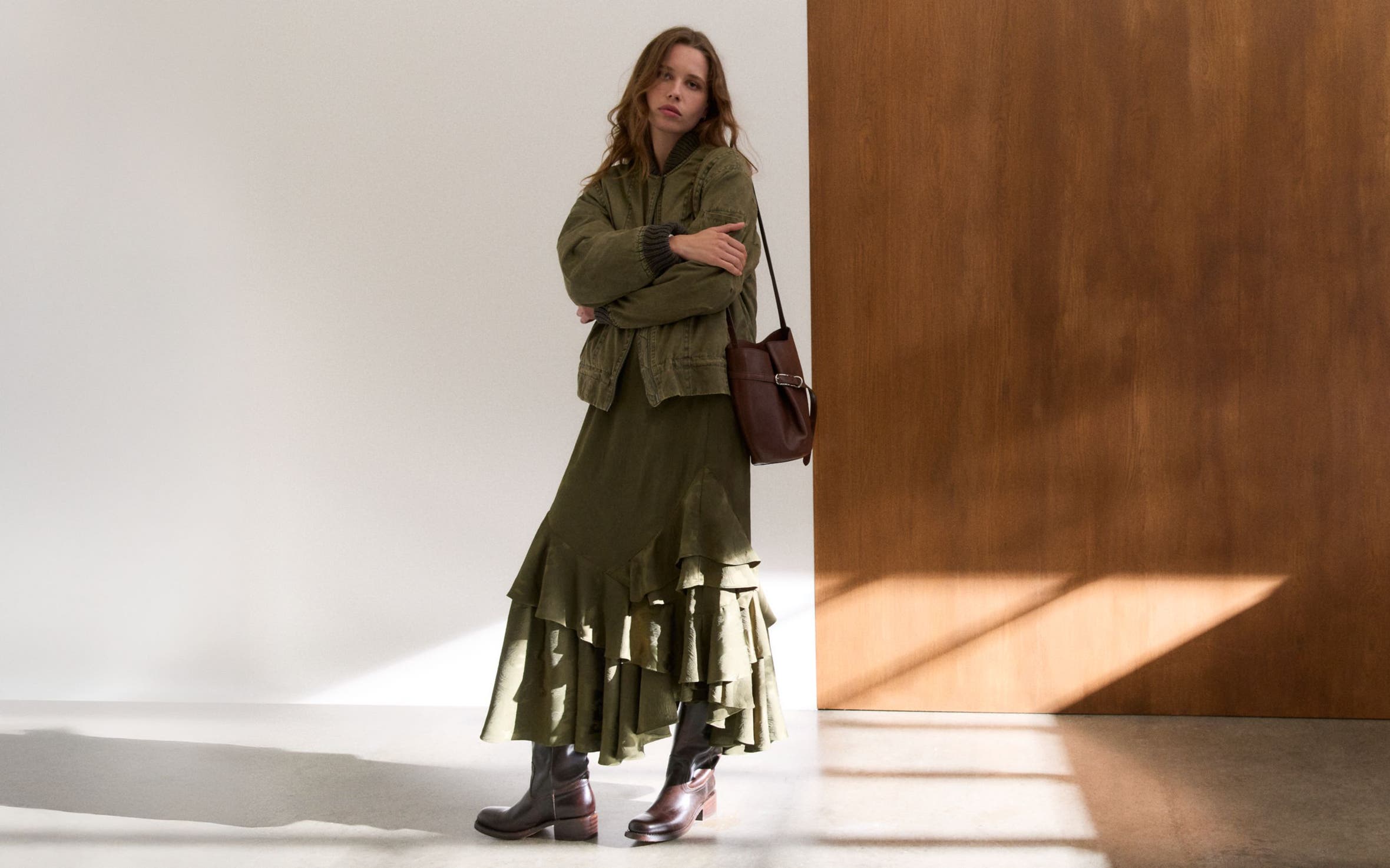 Woman wearing a bomber jacket, tiered skirt, bucket bag and boots.