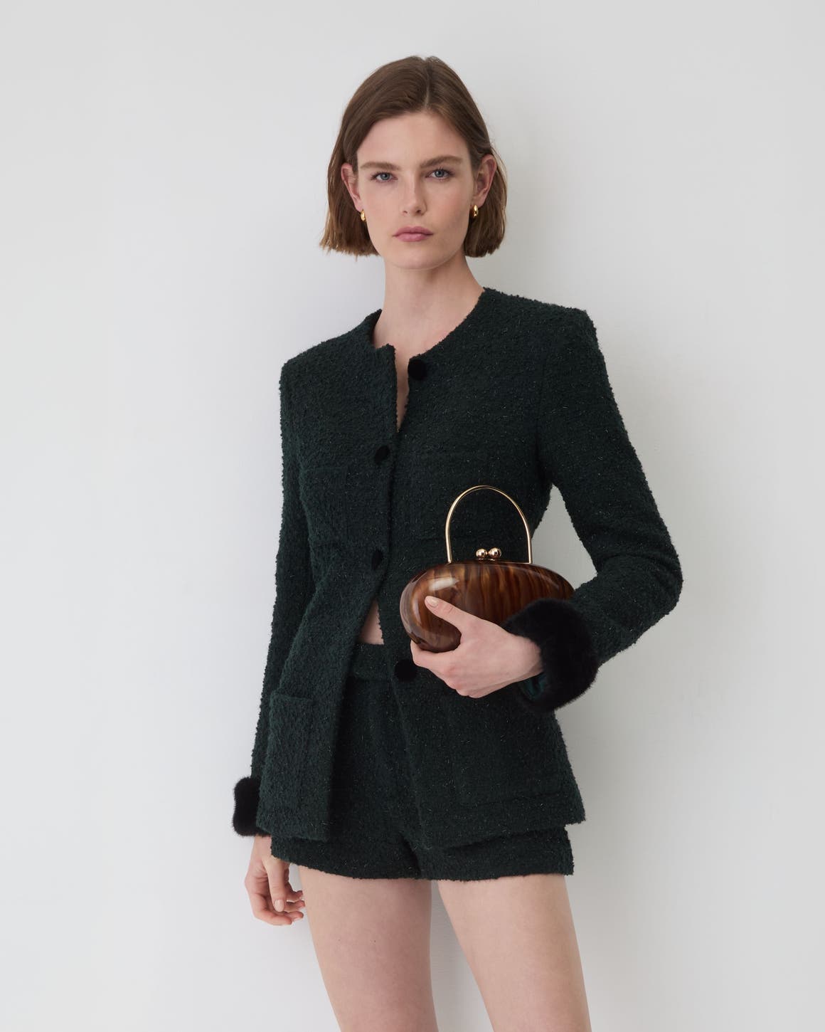 A woman wearing a black blazer and shorts.