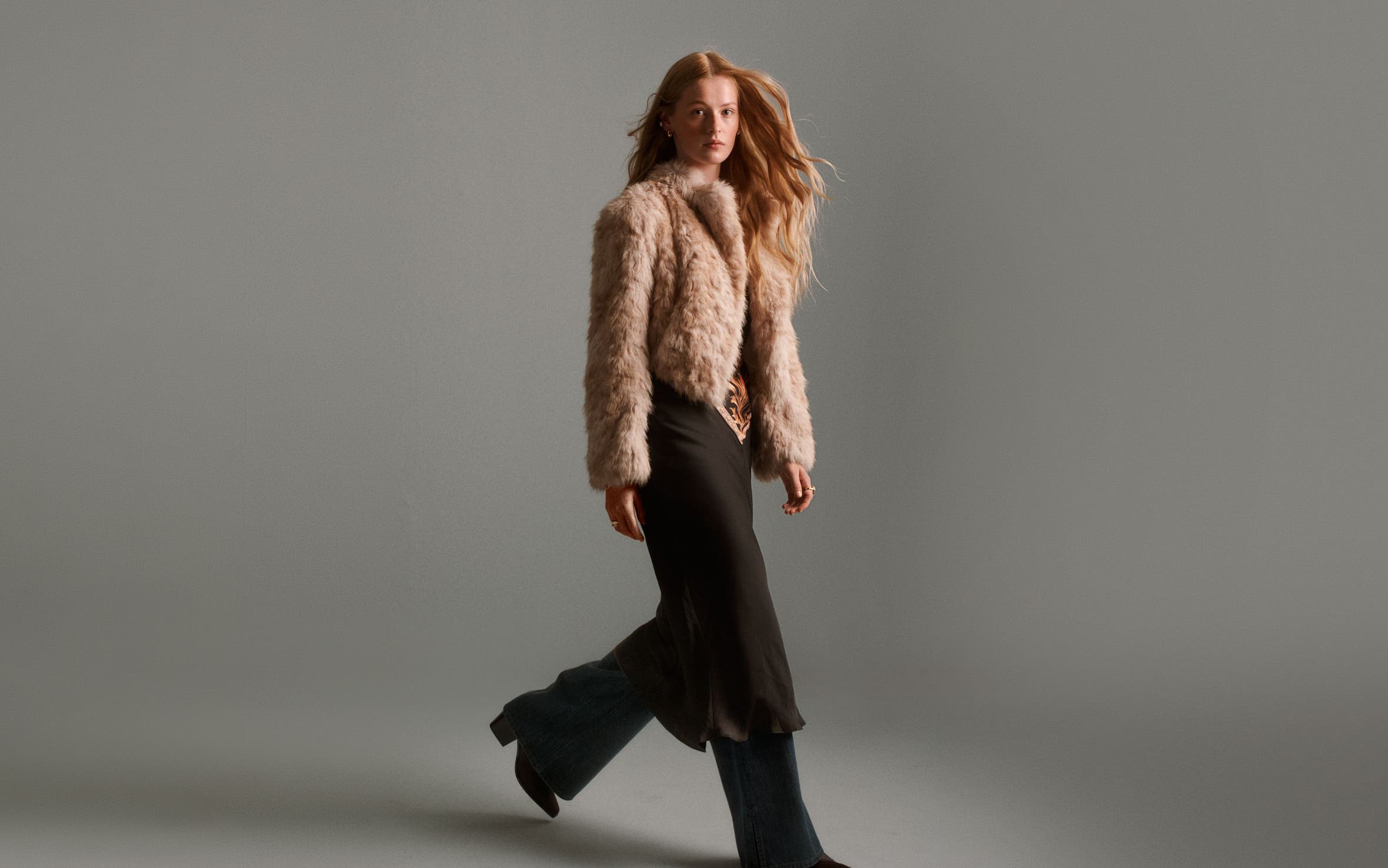 a girl walking with a fur jacket on