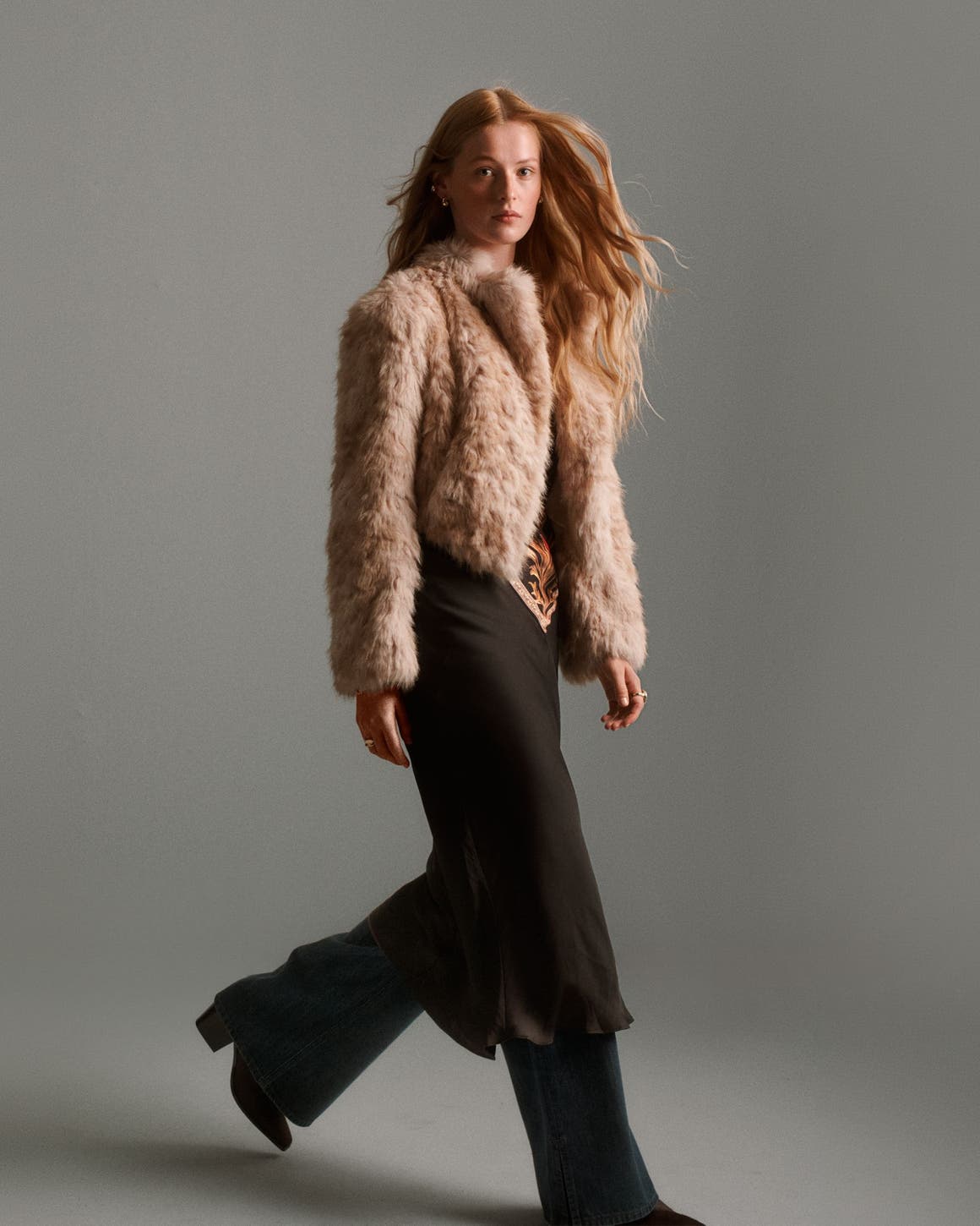 a girl walking with a fur jacket on