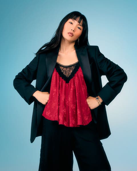 Model wearing a red lace cami top layered under an oversized black blazer with black pants.