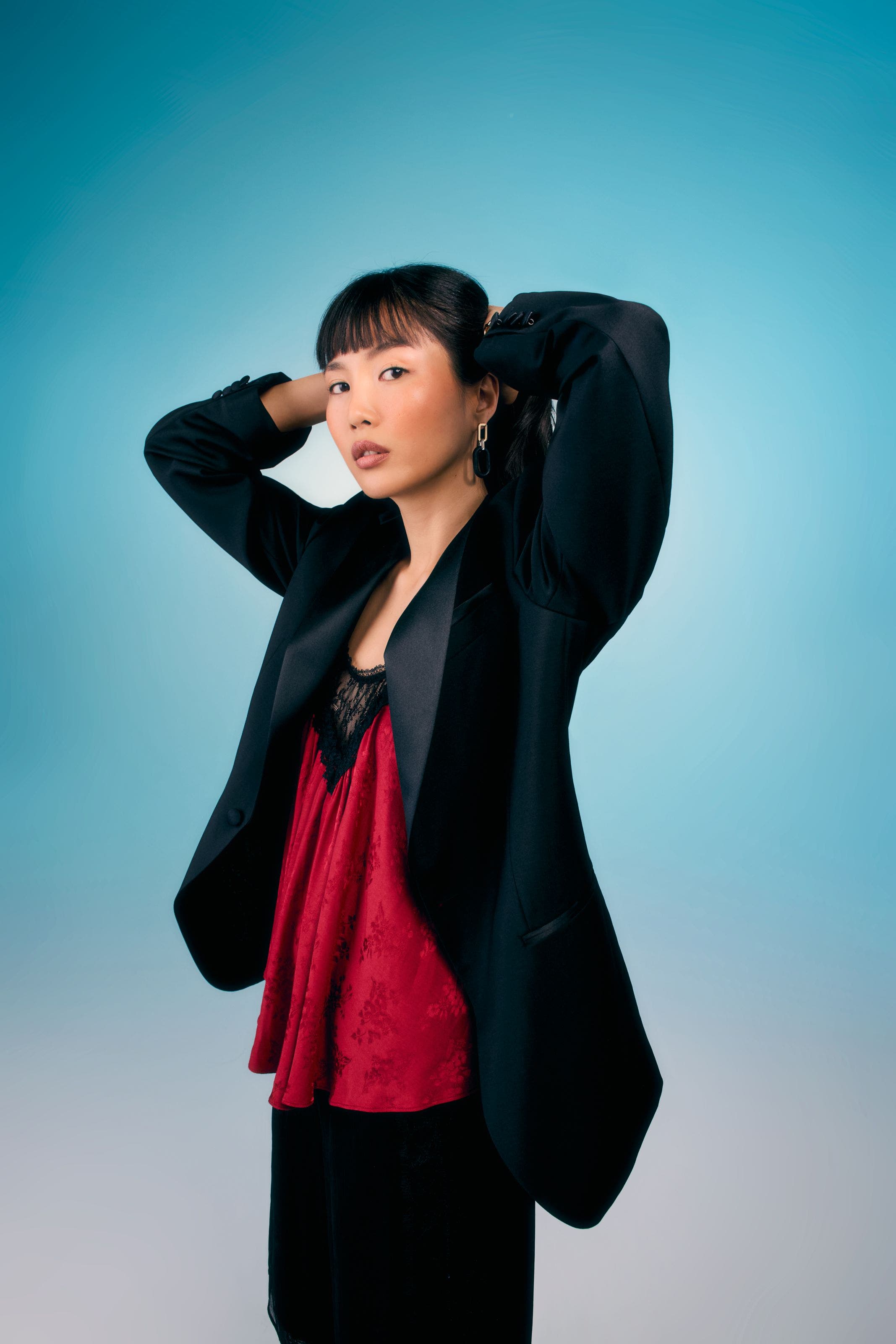 Woman wearing a black blazer over a red lace top.