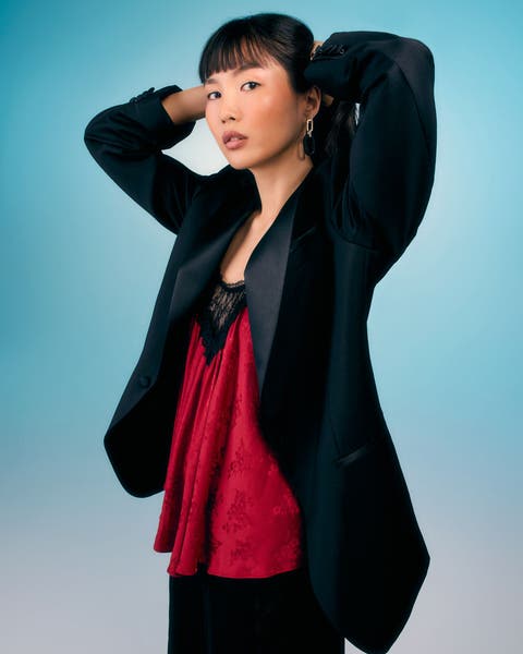 Woman wearing a black blazer over a red lace top.