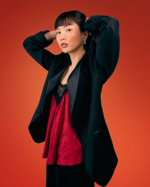 Woman in a black tuxedo blazer and red lace-trim camisole.