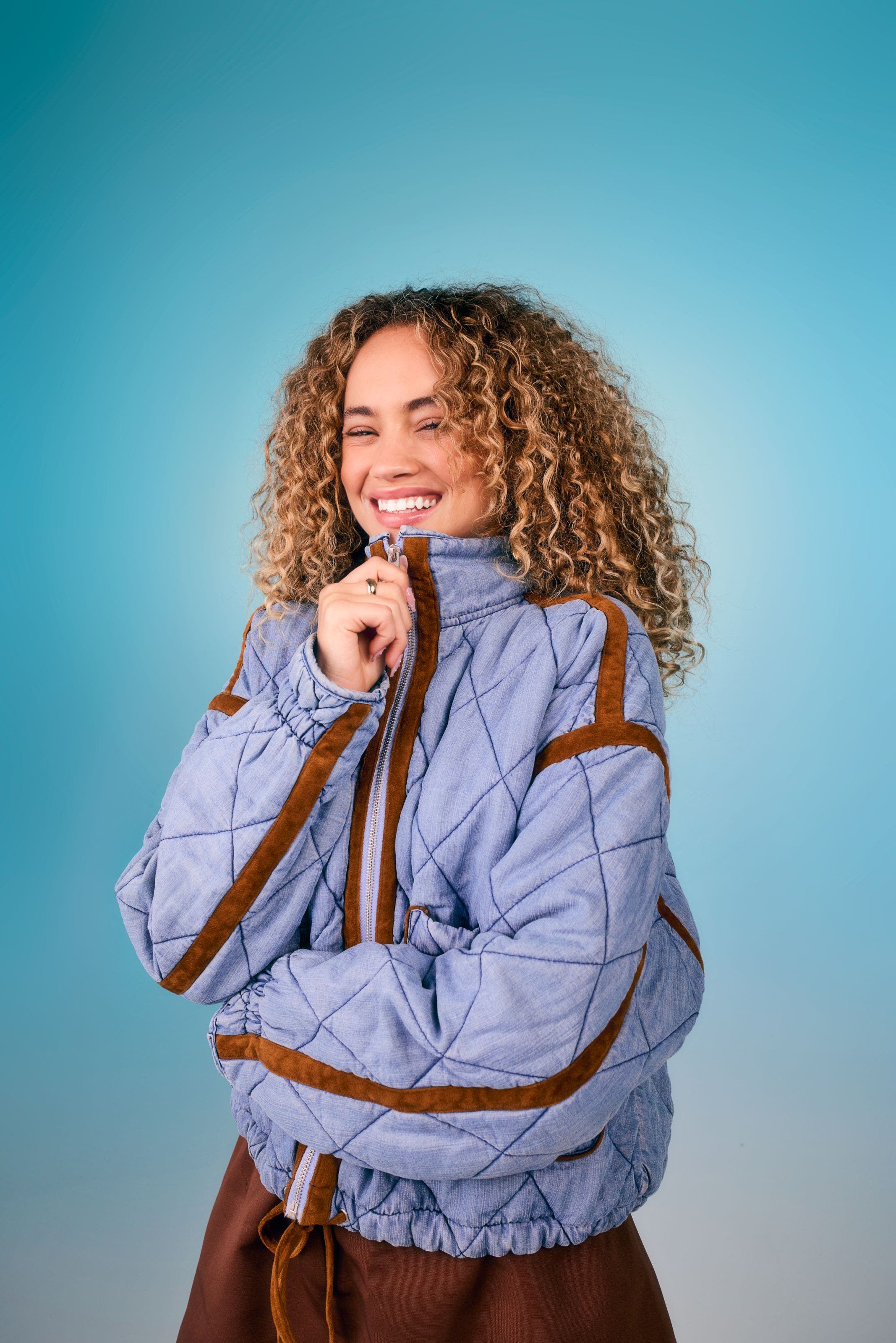 Model wearing a light blue quilted pullover jacket with brown trim detailing.