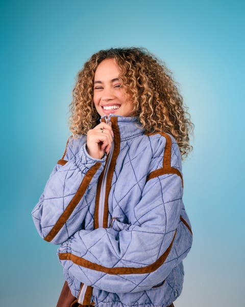Model wearing a light blue quilted pullover jacket with brown trim detailing.
