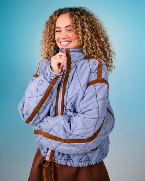 Model wearing a light blue quilted pullover jacket with brown trim detailing.