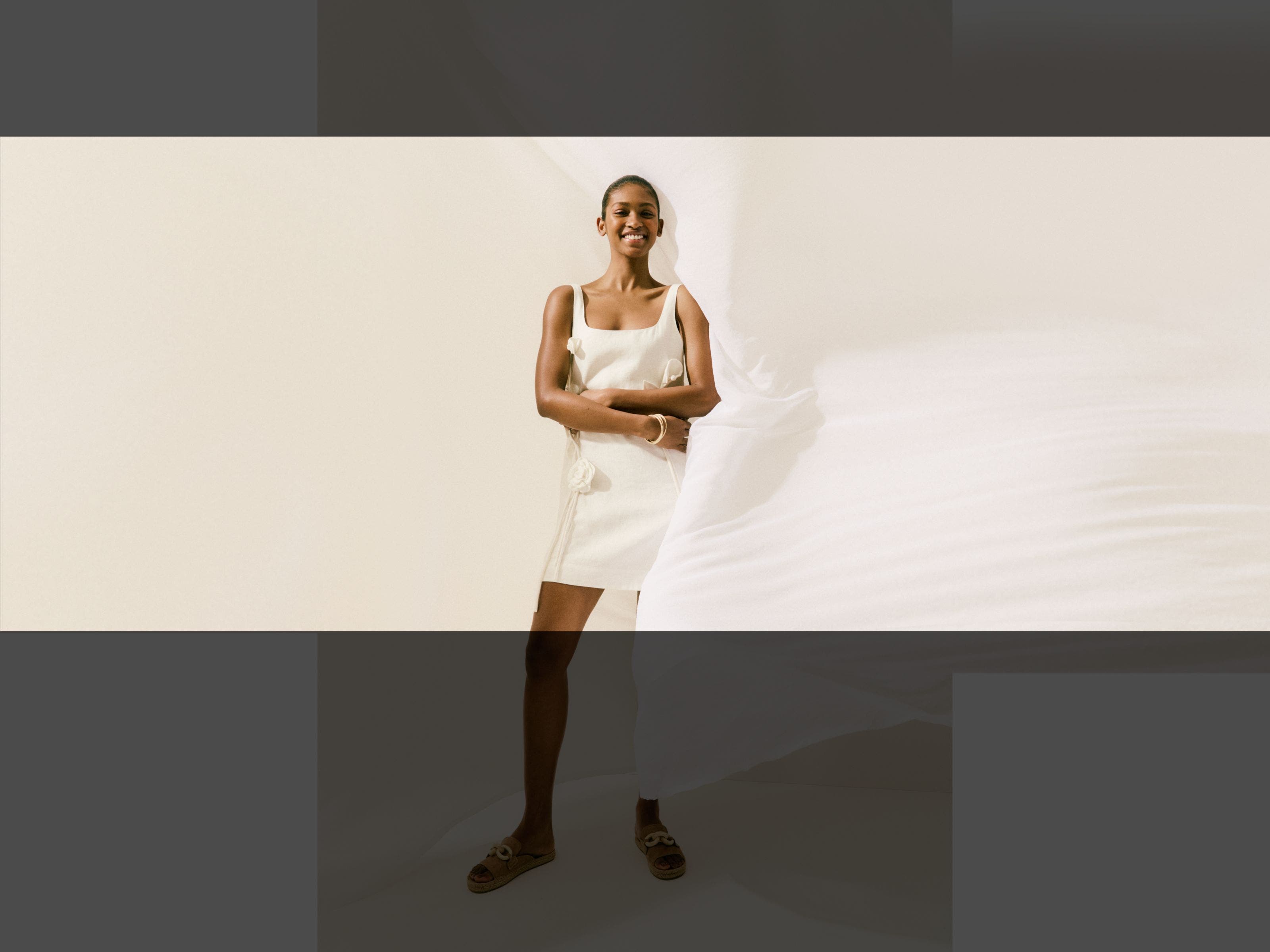 A woman wearing a white minidress with floral applique.