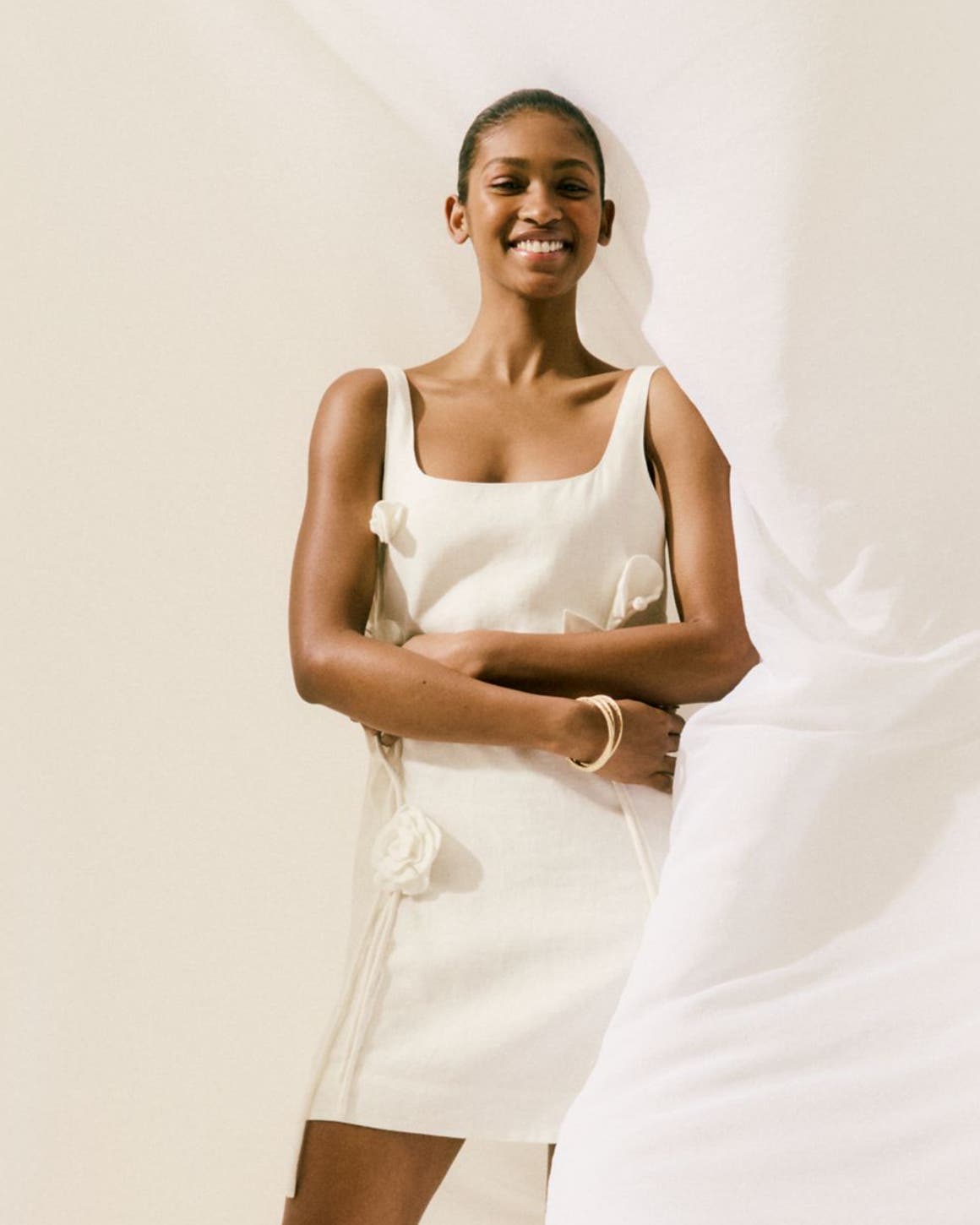 A woman wearing a white minidress with floral applique.