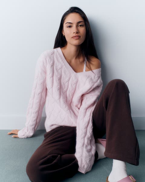 A woman in a pink cable-knit sweater.