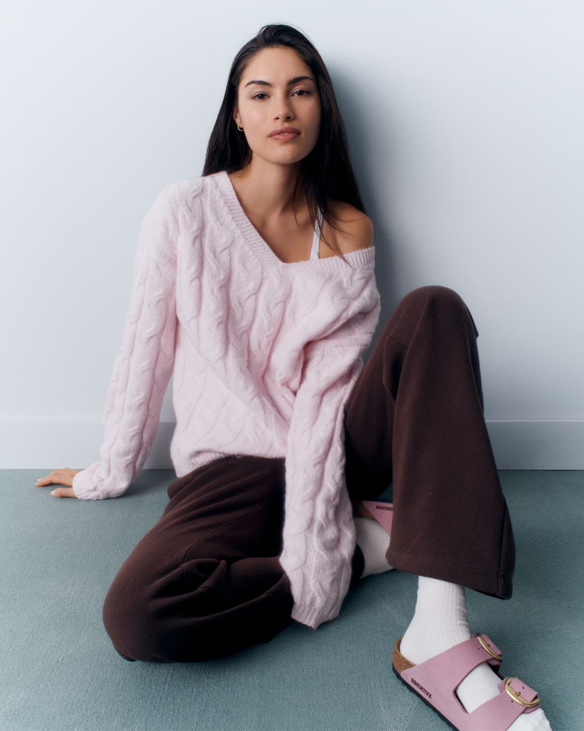 A young woman wearing a pink sweater, sweatpants and pink Birkenstock sandals; collage of women's knits, sneakers and campus essentials. 