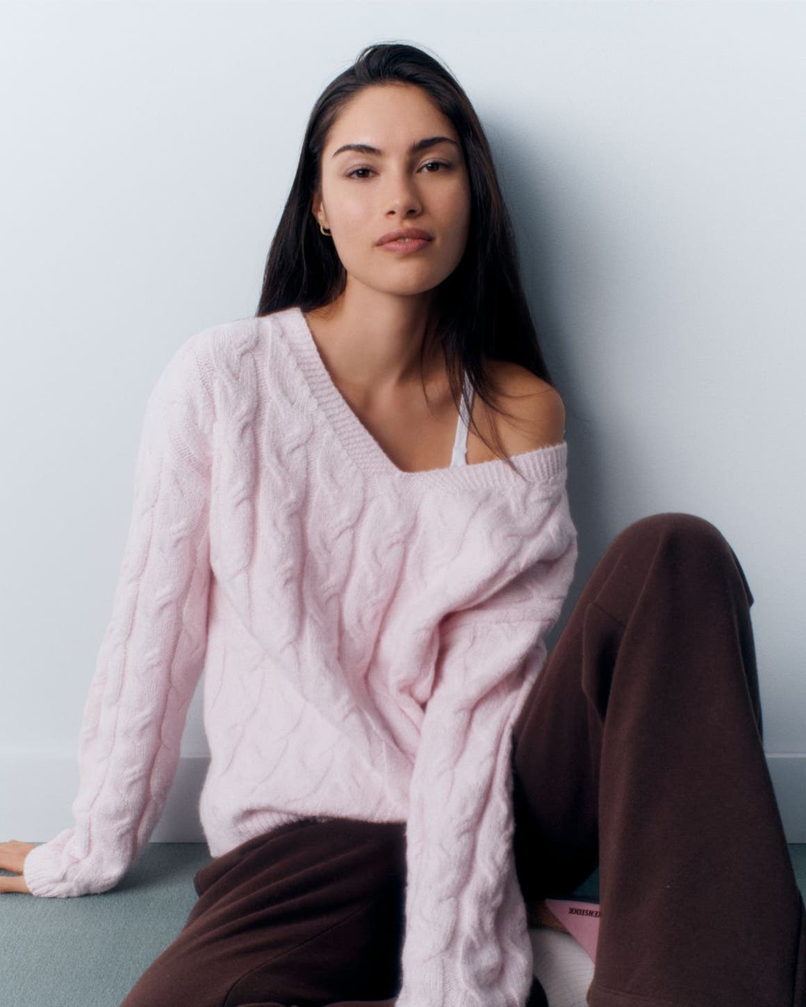 A woman wearing a pink sweater and brown pants.