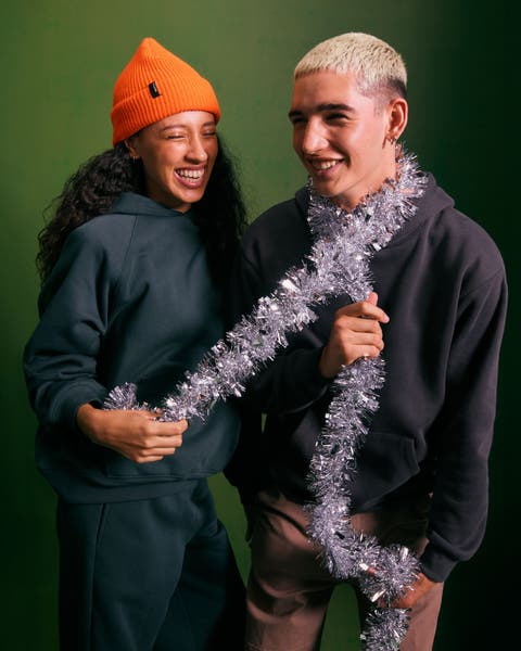 A teenage girl and boy playing with a silver garland.